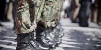 Soldiers in uniform and boots standing in formation.