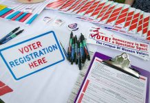 Voter registration table with forms, pens, and information.