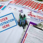 Voter registration table with forms, pens, and information.