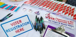 Voter registration table with forms, pens, and information.