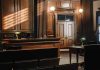 Empty courtroom with wooden interior and green lamps.