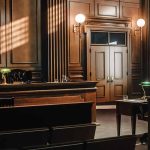 Empty courtroom with wooden interior and green lamps.