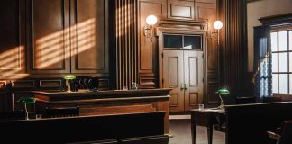 Empty courtroom with wooden interior and green lamps.