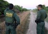 Two U.S. Border Patrol officers observing a dirt path.