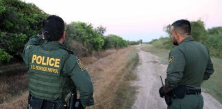 Two U.S. Border Patrol officers observing a dirt path.