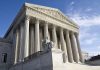 Supreme Court building with statue and columns.