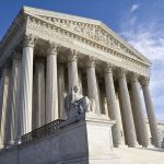 Supreme Court building with statue and columns.