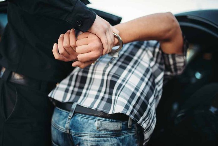 Person in handcuffs being arrested by police.