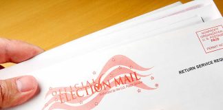 Hands holding official election mail envelope.