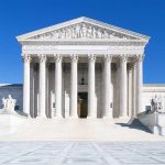 United States Supreme Court building under clear blue sky.