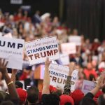 Crowd holding signs supporting Trump at a rally.