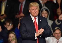 Man in suit clapping at public event.