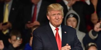 Man in suit clapping at public event.