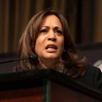 Woman speaking at a podium, serious expression.