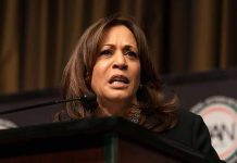 Woman speaking at a podium, serious expression.