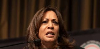 Woman speaking at a podium, serious expression.