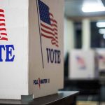 Voting booths with American flags and "Vote" signs.