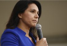 Woman in blue blazer holding a microphone.