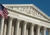 US Supreme Court building facade with flag.