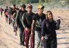 Line of people walking on a dirt road.