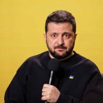 Man with microphone against a yellow background.