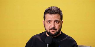 Man with microphone against a yellow background.