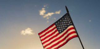 American flag waved against sunset sky.