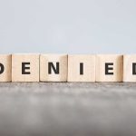 Wooden blocks spelling out "DENIED" in bold letters.