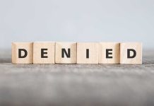 Wooden blocks spelling out "DENIED" in bold letters.