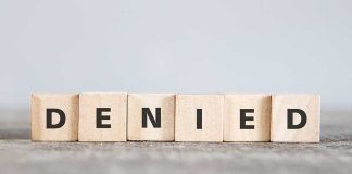 Wooden blocks spelling out "DENIED" in bold letters.