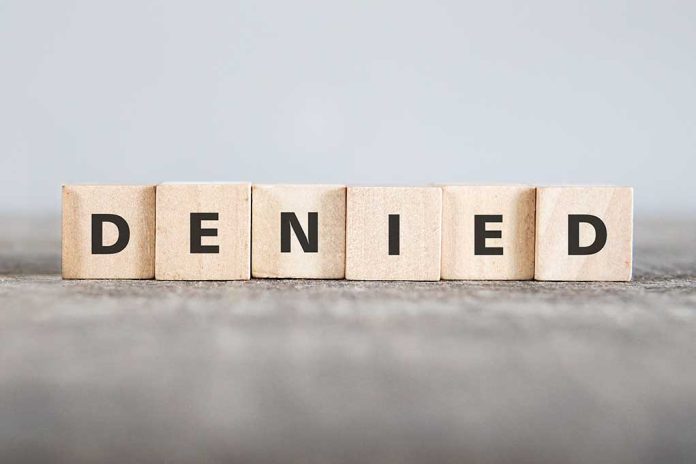 Wooden blocks spelling out "DENIED" in bold letters.