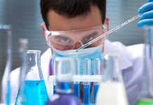 Scientist pipetting blue liquid into test tubes.