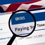 Magnifying glass over IRS website for paying taxes.