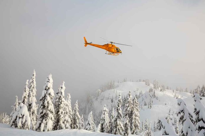 Yellow helicopter flying over snowy evergreen forest.