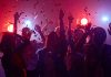 Partygoers dancing with confetti and colorful lights.