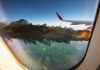 Airplane wing with engine on fire mid-flight.