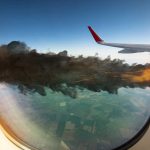 Airplane wing with engine on fire mid-flight.