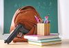 Gun and backpack on desk with school supplies.