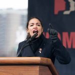 Person speaking passionately at an outdoor podium event