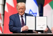 Man holding signed document with three visible flags