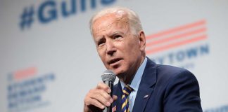 Man speaking into microphone wearing suit and tie