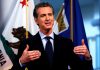 Man speaking in front of California flag backdrop