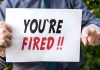 Person holding "YOU'RE FIRED" sign.