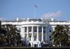 White House with American flag flying, daytime.