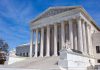 Supreme Court building with columns and statues.