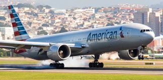 Airplane landing on runway with cityscape background.