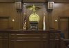 Empty courtroom with judge's chair and American flag.