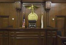 Empty courtroom with judge's chair and American flag.