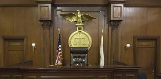 Empty courtroom with judge's chair and American flag.