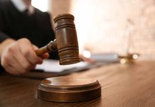 Judge with gavel on wooden desk courtroom setting